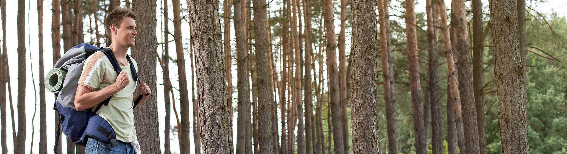 man hiking with backpack through a forest.